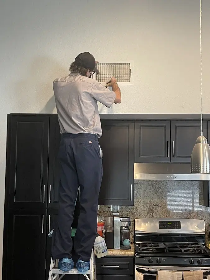 Technician inspecting an air vent during HVAC service in Springfield